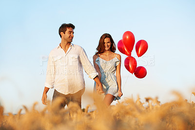 Buy stock photo Happy, couple and holding hands in countryside with balloons, portrait and bonding for anniversary. Married people, walk and romantic gesture in wheat field with relationship, love and commitment.