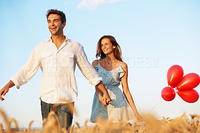 Buy stock photo Balloons, holding hands and smile with couple in field for spring date, honeymoon getaway or bonding. Trust, holiday and connection with man and woman in countryside for romance, celebration and care