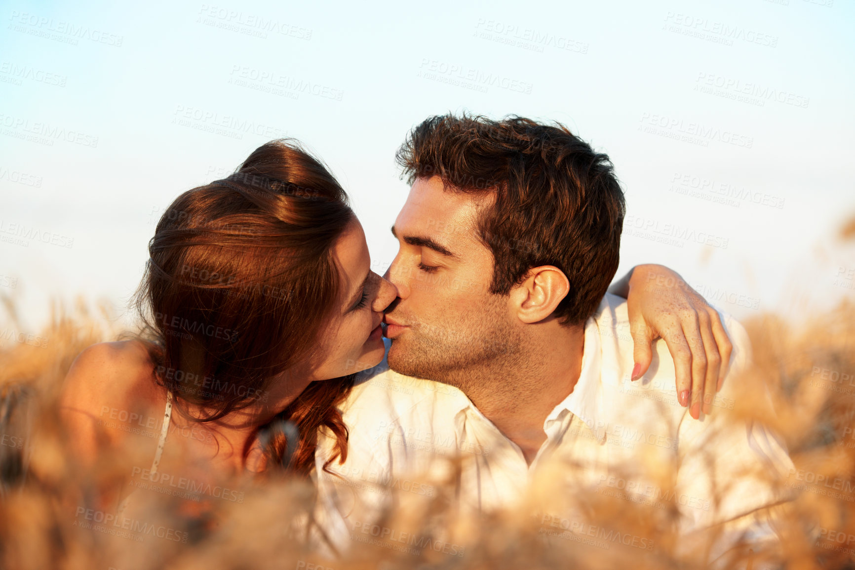 Buy stock photo Countryside, couple and relax in field with kiss, romantic getaway and bonding together for vacation. Happy, married people and outdoor with summer holiday, caring relationship or affection for love.