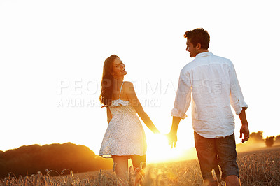 Buy stock photo Holding hands, sunset and walking with couple in field for honeymoon getaway, support or trust. Space, connection and date with man and portrait of woman in countryside for loyalty, holiday or travel