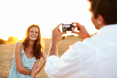 Buy stock photo Woman, sunset and camera with couple in meadow, photography or memory of honeymoon. Female person, smile and nature with man and digital tech for picture taking, anniversary trip and relationship 