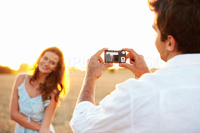 Buy stock photo Woman, sunset and camera with couple outdoor, photography or memory of honeymoon. Female person, smile and nature with man and digital tech for picture taking, anniversary trip and relationship 