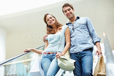 Buy stock photo Retail, couple and smile with bags on escalator for clearance sale, weekend outing or support. Mall, people and portrait on shopping spree for store promotion, fashion deal and bonding on low angle