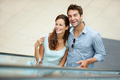 Buy stock photo Happy, shopping and escalator with couple in mall for retail purchase, anniversary gift and support. Store discount, customer promotion and love with man and woman with bags for boutique shopper