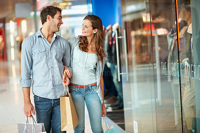 Buy stock photo Happy, couple and hug in mall with shopping bag, conversation and bonding together on weekend break. People, dating and walk by store with retail purchase, cashback promotion and talk about discount.