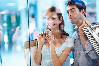 Buy stock photo Couple, decision and window shopping with paper bag in mall, bonding or search for sale with partner. Boutique, glass and happy people with purchase choice, discussion and pointing at discount deals
