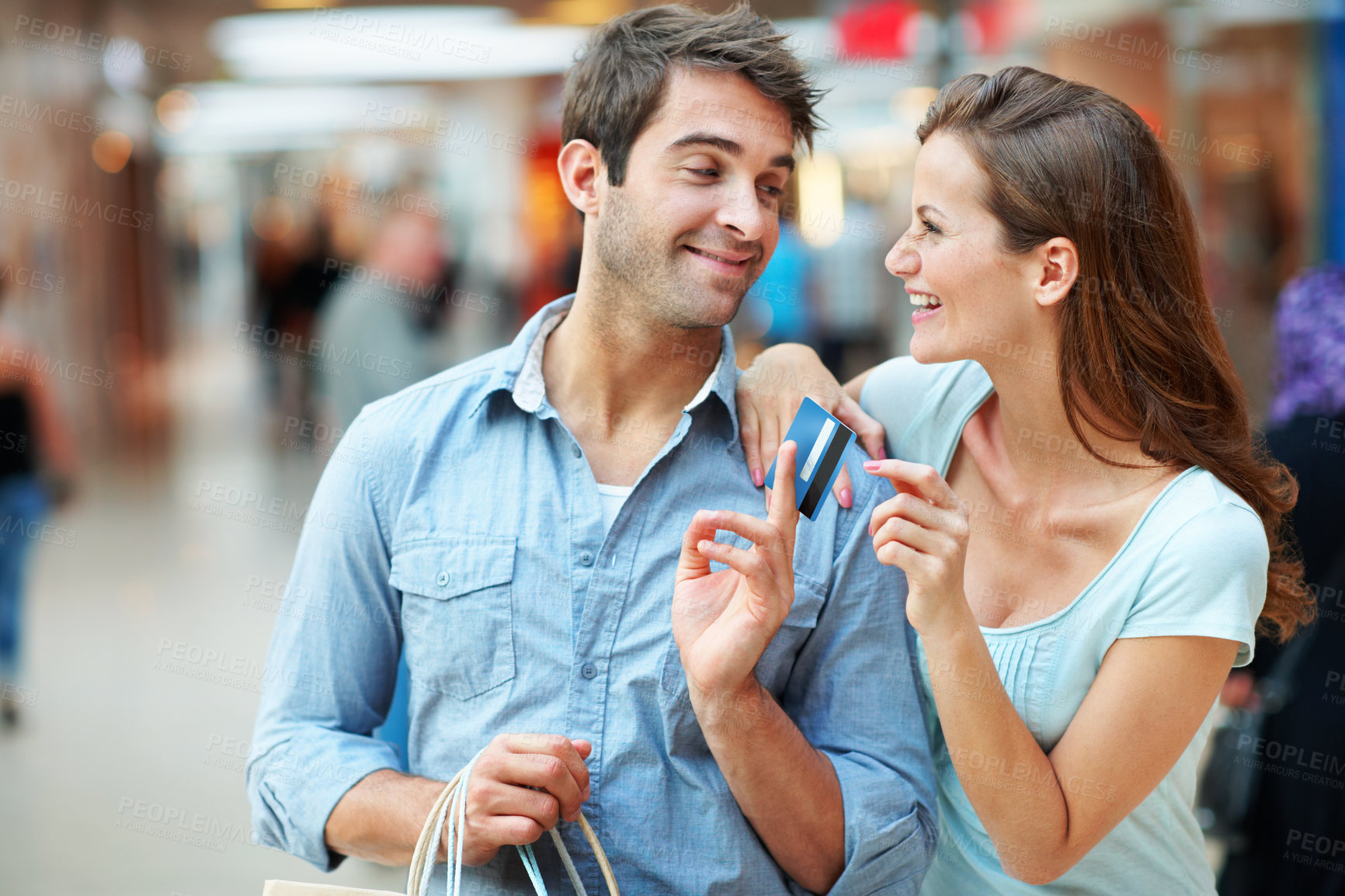 Buy stock photo Happy, couple and shopping with credit card in mall for payment, purchase or banking offer. Woman, man and giving debit with smile or gift bags for finance, love or care in commercial center or store