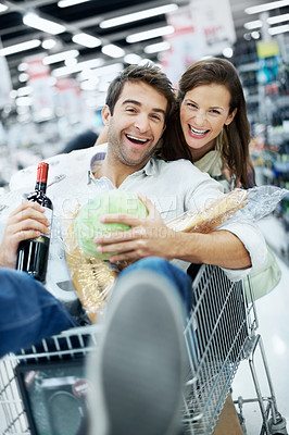 Buy stock photo Portrait, playful and couple with shopping cart in store for groceries, bonding and relationship fun. Dating, laugh and woman pushing man in trolley for connection, love and trust in supermarket