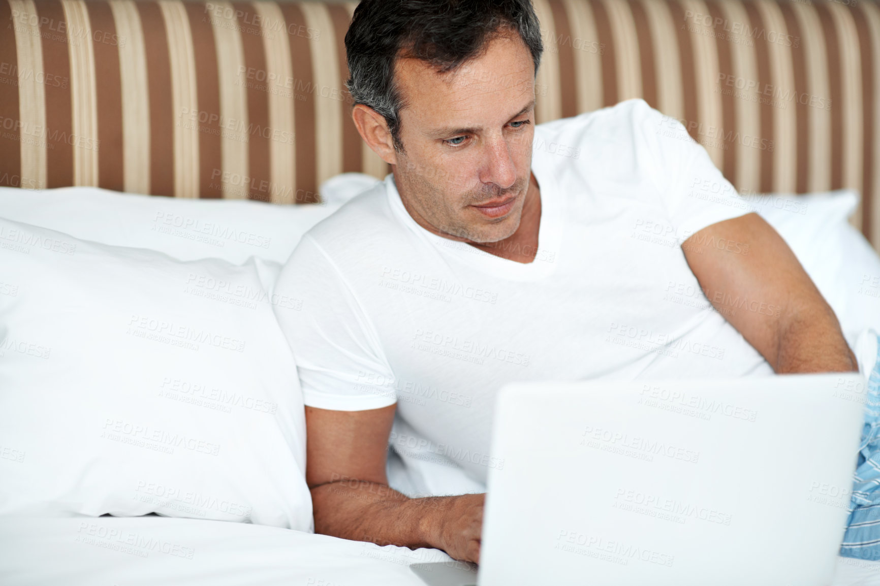 Buy stock photo Man, laptop and relax in bed with streaming, movies and search for series on web in home. Mature person, computer and break with film, subscription and show in morning with pyjamas at apartment