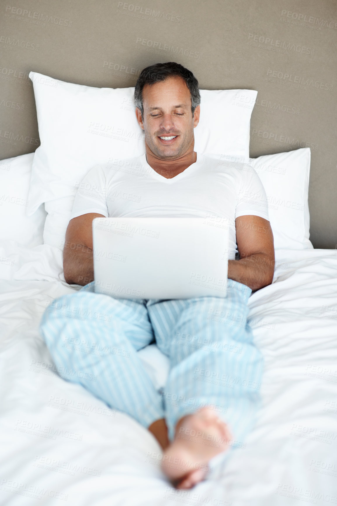 Buy stock photo Relax, man and happy with laptop on bed for binge watching series, movie and peaceful morning. Comfort, mature person and tech in bedroom for streaming film, tv show episode or weekend break in home