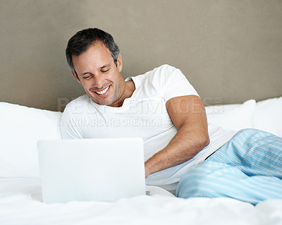 Buy stock photo Morning, man and relax with laptop on bed for series subscription, movie and peaceful holiday. Happy, mature person or tech in bedroom for streaming film, tv show or comfortable weekend break in home