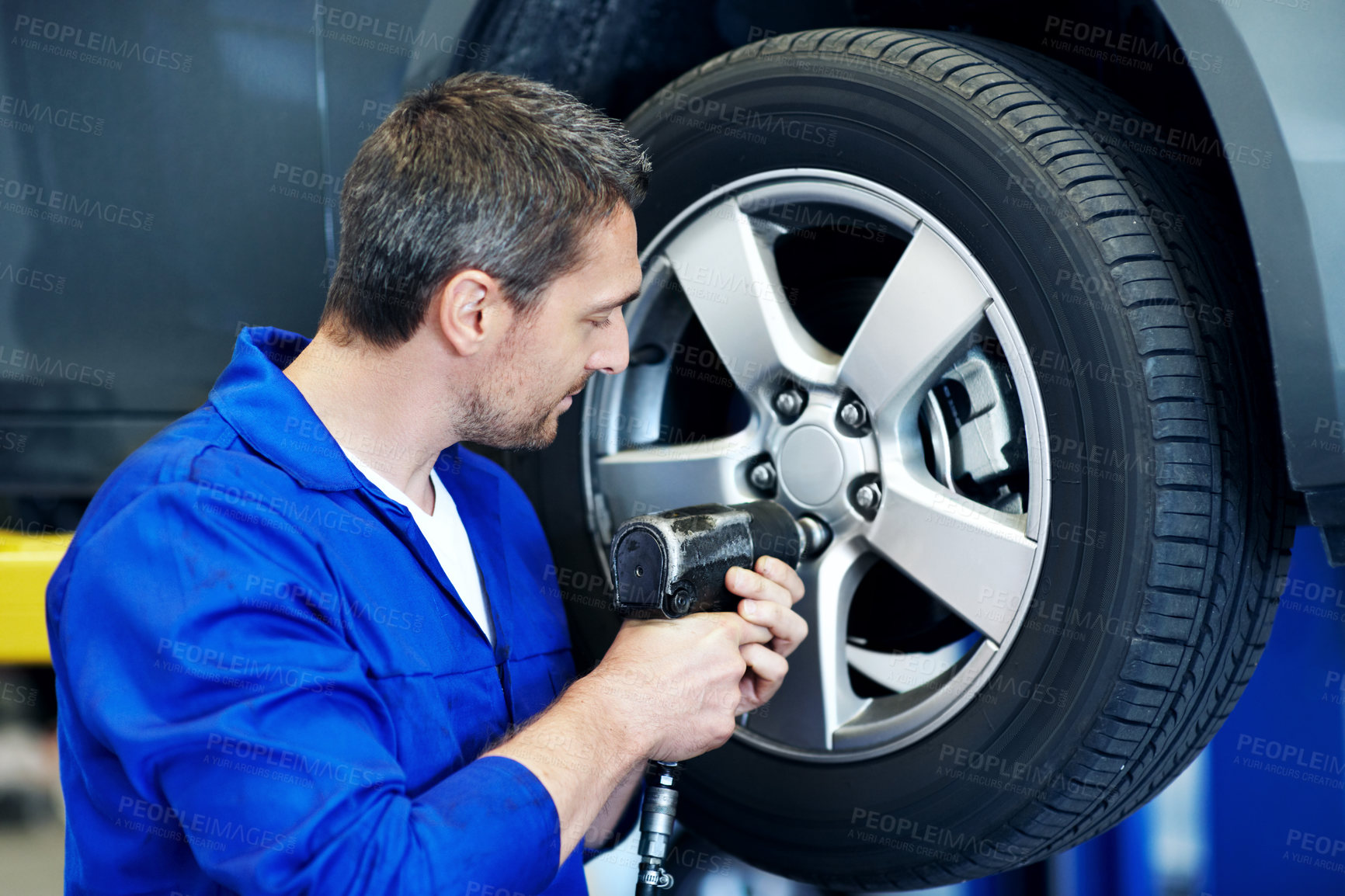 Buy stock photo Workshop, mechanic and man with drill for tire alignment, repair and maintenance for auto service. Garage, technician and person with equipment for fixing, installation and inspection for vehicle