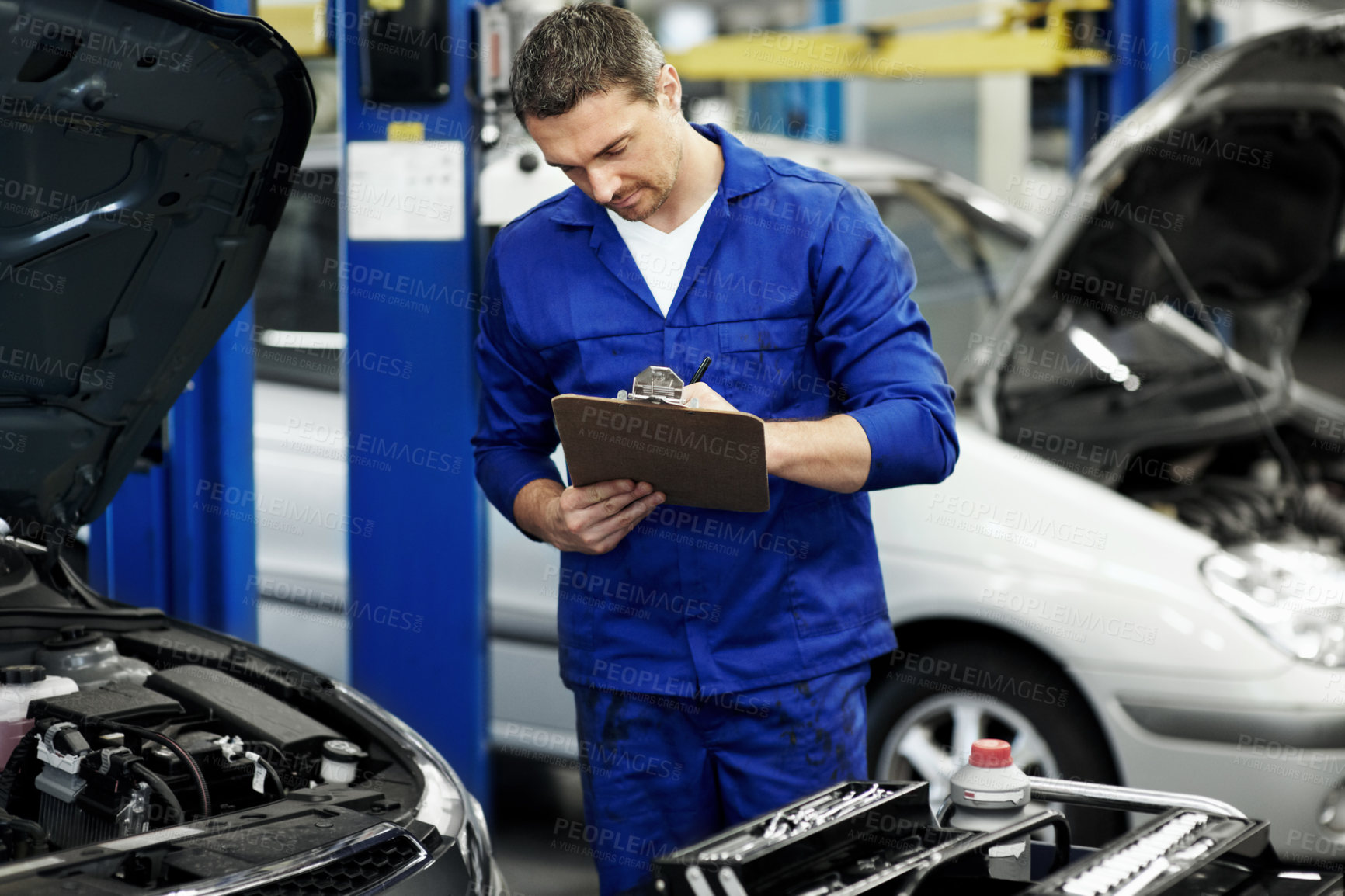 Buy stock photo Man, mechanic and clipboard for car at workshop for notes, writing information or repair services. Person, technician or engineer with vehicle, maintenance checklist and inspection at auto garage