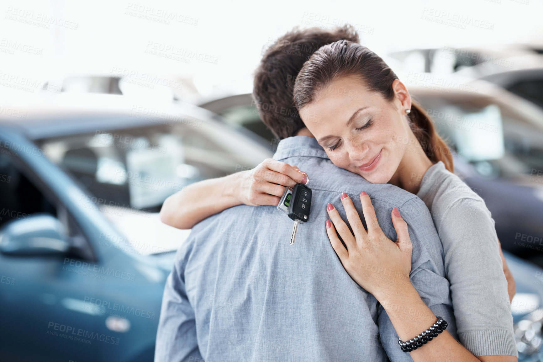 Buy stock photo Couple, hug and smile with new car for dealership purchase, appointment and celebration. Loan approval, showroom and people shopping for motor rental, embrace and investment for transportation