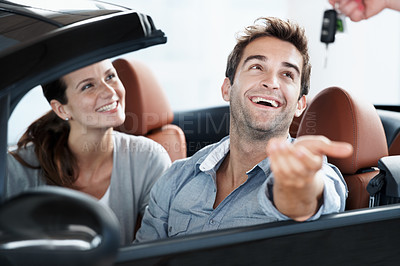 Buy stock photo Couple, laugh or key at car dealership with salesperson for purchase, sale or test drive in automobile. Man, woman and giving keychain in convertible for vehicle ownership, excited or transportation