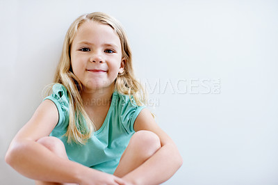Buy stock photo Portrait of a pretty little blonde girl sitting in front of a white wall