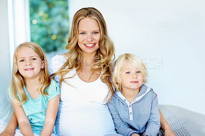 Buy stock photo Portrait of a pregnant mother with her little son and daughter sitting together at home