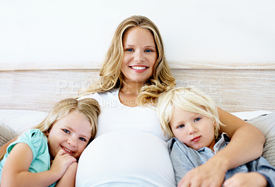 Buy stock photo Portrait of a pregnant mother with her little son and daughter sitting together at home