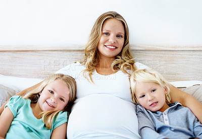 Buy stock photo Portrait of a pregnant mother with her little son and daughter sitting together at home