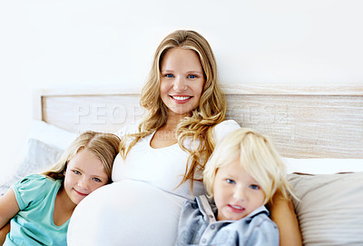 Buy stock photo Portrait of a pregnant mother with her little son and daughter sitting together at home