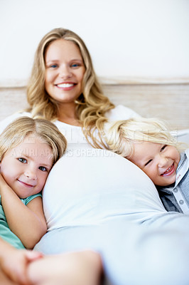 Buy stock photo Portrait of a pregnant mother with her little son and daughter sitting together at home