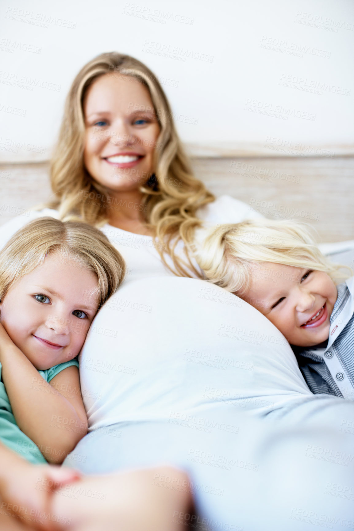 Buy stock photo Portrait of a pregnant mother with her little son and daughter sitting together at home
