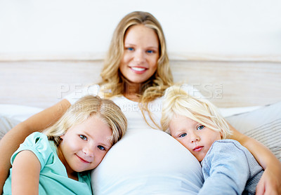 Buy stock photo Portrait of a pregnant mother with her little son and daughter sitting together at home