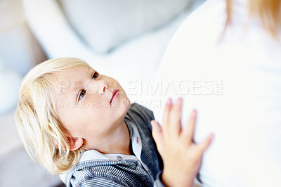 Buy stock photo A little boy with his hands on his mother's pregnant belly
