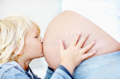 Buy stock photo A little boy kissing his mother's bare pregnant belly