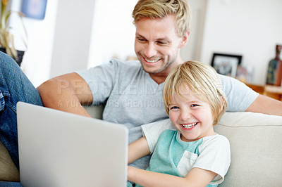 Buy stock photo Cute little boy having fun with his dad and their laptop on the couch