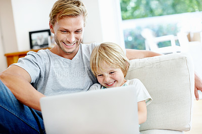 Buy stock photo Cute little boy having fun with his dad and their laptop on the couch
