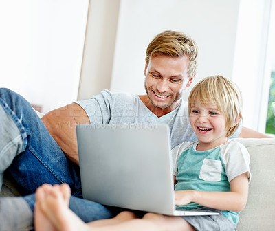 Buy stock photo Cute little boy having fun with his dad and their laptop on the couch