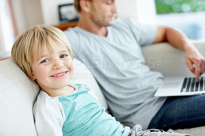Buy stock photo Cute little boy smiling at you while his dad is working on his laptop at home