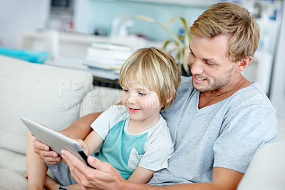 Buy stock photo Loving father teaching his cute little son to use their new digital tablet