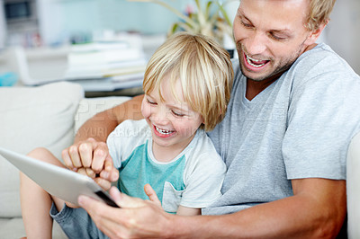 Buy stock photo Loving father and son laughing while playing a game on a digital tablet at home
