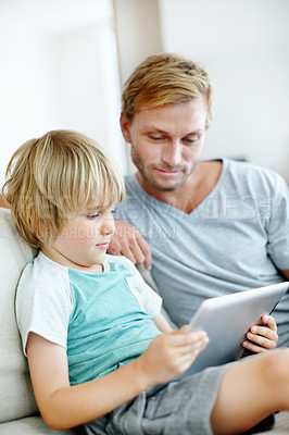 Buy stock photo Cute little boy learning how to use a digital tablet with his dad at home