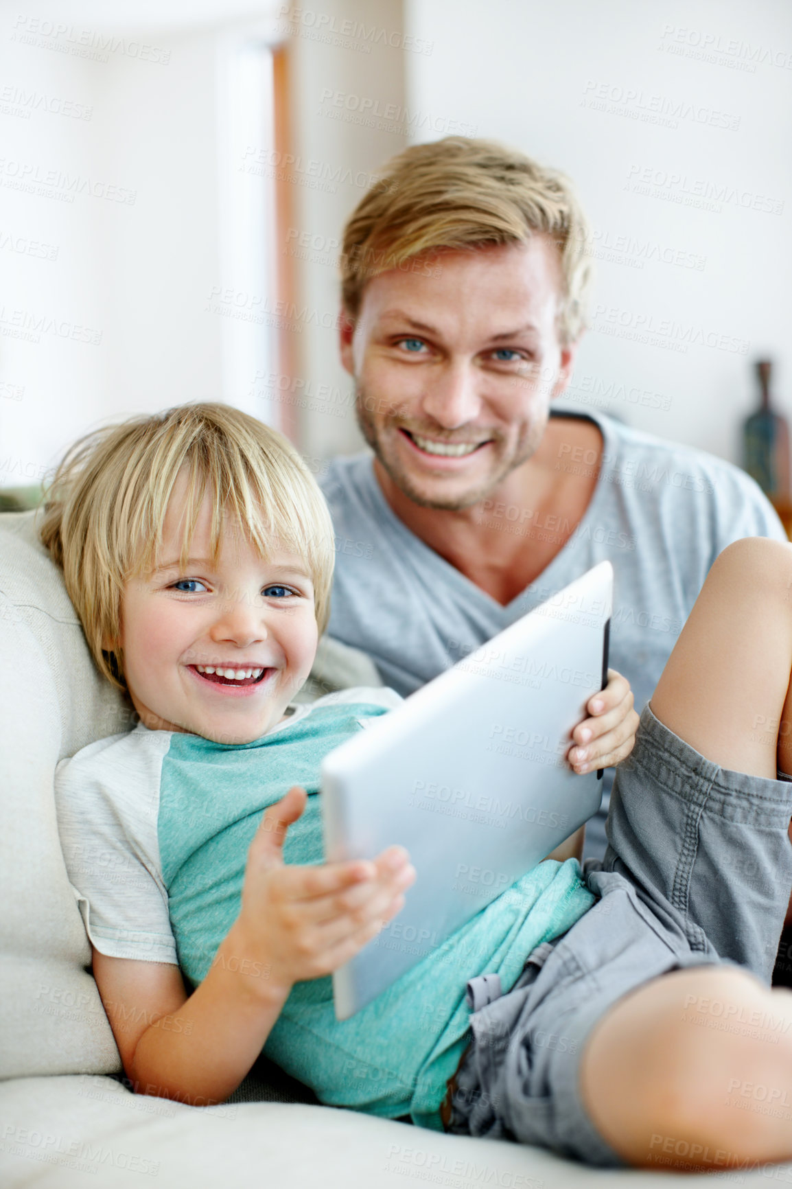 Buy stock photo Handsome dad and his cute son smiling at the camera with their digital tablet at home
