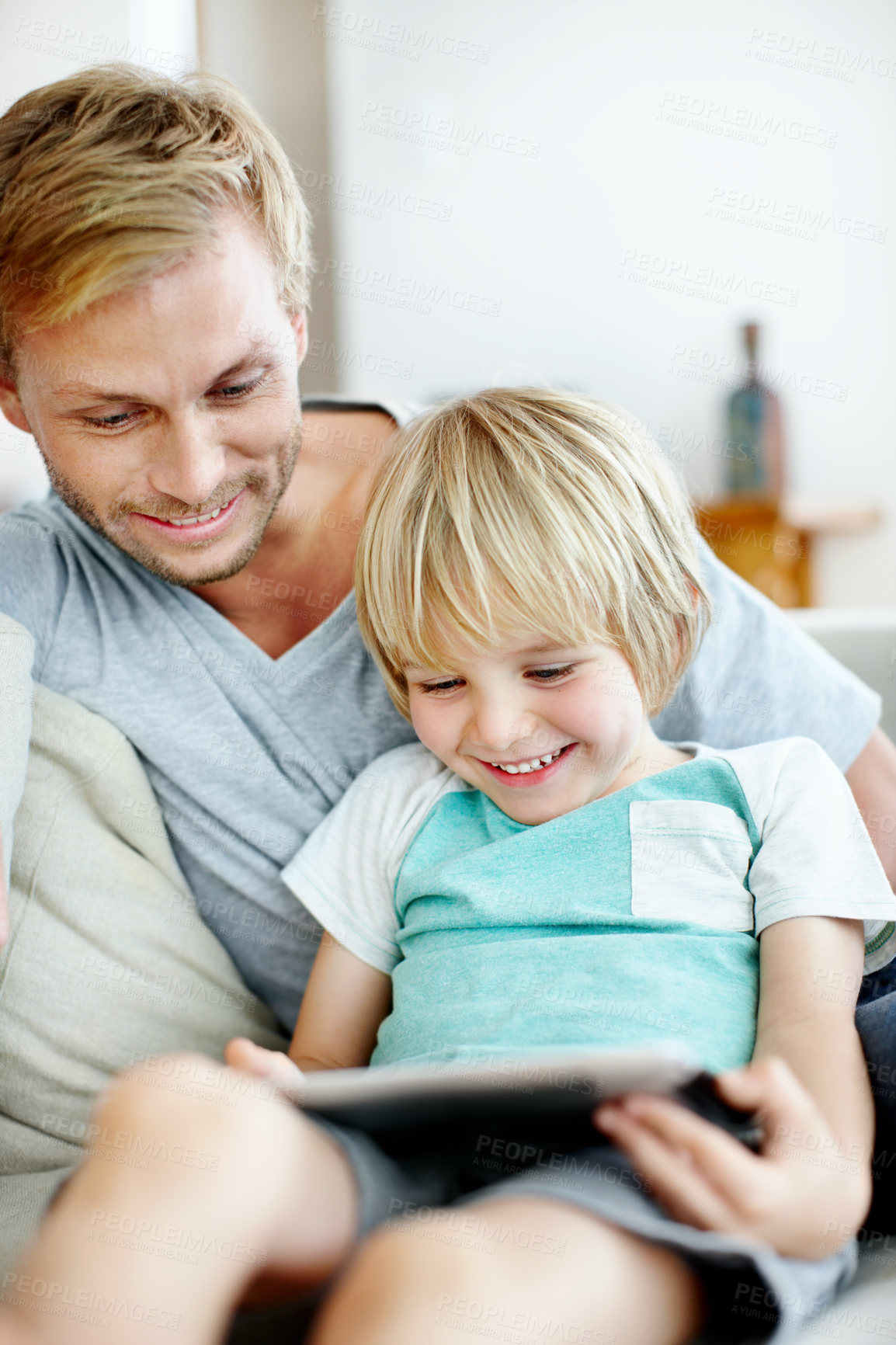 Buy stock photo Cute little boy learning how to use a digital tablet with his dad at home