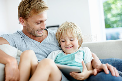 Buy stock photo Cute little boy resting on the couch with his loving dad using a digital tablet