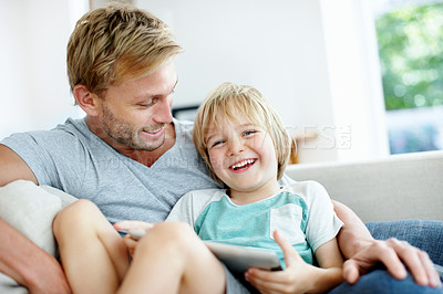 Buy stock photo Laughing little boy resting on the couch with his loving dad using a digital tablet