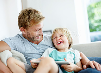 Buy stock photo Cute little boy having fun on the couch with his loving dad using a digital tablet