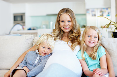 Buy stock photo Pregnant young mom sitting with her two young children on the sofa