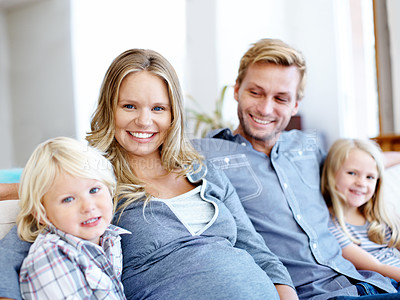 Buy stock photo Cute young family of four sitting together on the sofa at home