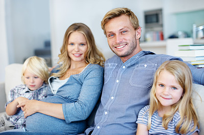 Buy stock photo Cute young family of four sitting together on the sofa at home