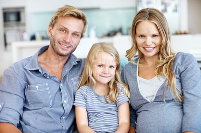 Buy stock photo Cute little girl sitting on the sofa with her father and pregnant mother