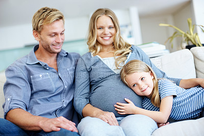 Buy stock photo Cute little girl sitting on the sofa with her father and pregnant mother and listening to her mother's belly