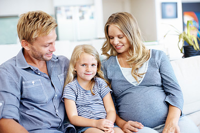 Buy stock photo Cute little girl sitting on the sofa with her father and pregnant mother
