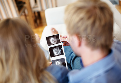Buy stock photo Young couple looking at the ultrasound scan pictures of their unborn baby