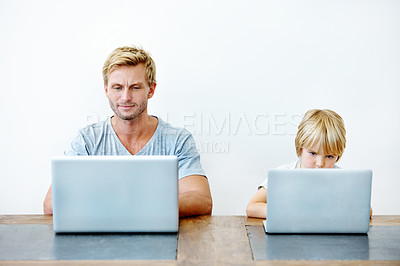 Buy stock photo A young father and his son sitting together on their laptops