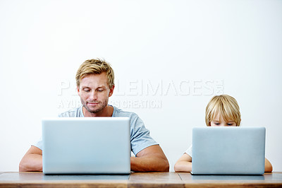 Buy stock photo A young father and his son sitting together on their laptops